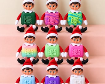 May include: Nine elf dolls with brown hair, red and white hats, and red and white striped legs. Each elf holds a square Nee Doh fidget toy in various colors including green, purple swirl, lime, rainbow, light green, pink, blue, violet, and white.