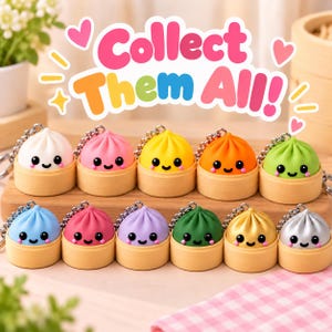 May include: A collection of eleven colorful dumpling keychains, each featuring a smiling face and resting in a small bamboo steamer base. The text "Collect Them All!" is displayed in large, vibrant, multi-colored letters above the items.