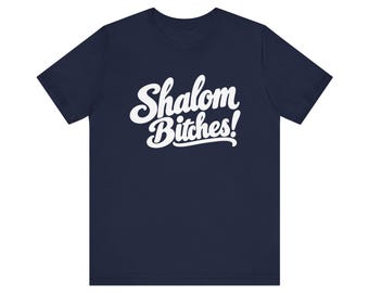 May include: A navy blue short-sleeve t-shirt featuring the white text Shalom Bitches! printed in a bold, cursive script across the center of the chest. The garment has a crew neckline and a standard fit with short sleeves.