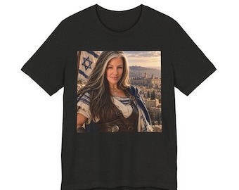 May include: A black short-sleeved t-shirt featuring a centered graphic print of a person with long gray and brown hair, wearing a brown leather-style vest over a white shirt, with an Israeli flag and a stone city landscape in the background.
