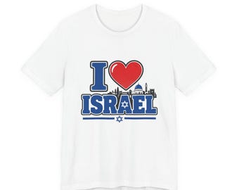 May include: A white short-sleeved t-shirt featuring a graphic print that says I heart ISRAEL in blue letters with a red heart. The design includes a black silhouette of a city skyline and a small blue Star of David centered below the text.