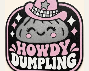 Op de afbeelding: Een sticker met een grijs knoedelkarakter dat een roze cowboyhoed met een ster draagt. De achtergrond is zwart met roze en witte sterretjes. Onder het karakter staat de tekst HOWDY DUMPLING in dikke, witte en roze letters geschreven.