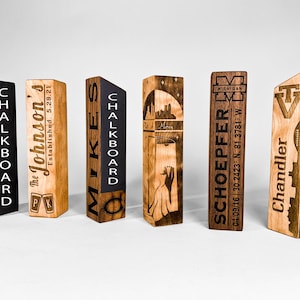 May include: Five wooden tap handles with black chalkboard inserts. The handles are engraved with various designs and text, including a brewery logo, a business name, a city skyline, a state name, and a business name with a location.