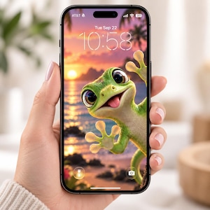 May include: A black smartphone displaying a lock screen with a digital wallpaper of a green gecko with large eyes and a small tongue sticking out, set against a sunset beach background with the time 10:58 and the date Tue Sep 22 visible.