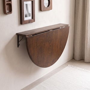 May include: A wall-mounted, dark brown wooden drop-leaf table featuring a semi-circular folding surface attached to a rectangular shelf with metal hinges and support brackets, showcasing a natural wood grain finish throughout the structure.