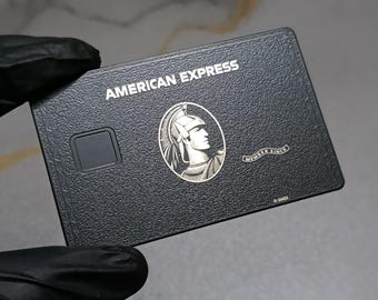 Op de afbeelding: Een zwarte American Express creditcard met een getextureerd oppervlak. De kaart bevat de witte tekst AMERICAN EXPRESS, een zilveren centurion-logo in een ovaal kader, een zwarte vierkante chip en een klein lint met de tekst MEMBER SINCE.