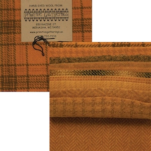 May include: Hand-dyed wool fabrics in orange, brown, and olive green. The fabrics display plaid and herringbone patterns. A tag reads "Primitive Gatherings" with contact details. The fabrics are suitable for various craft projects.
