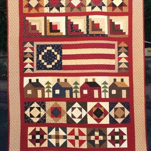 Peut inclure: Une courtepointe faite à la main sur le thème patriotique. La courtepointe présente des blocs avec des motifs d'étoiles, des motifs de cabanes en rondins et un drapeau américain. La palette de couleurs comprend le rouge, le blanc, le bleu et le beige. La courtepointe mesure environ 183 cm x 213 cm.
