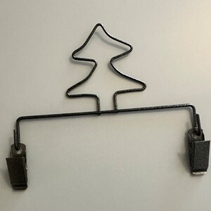 May include: Black metal Christmas tree-shaped hanger with two clips.
