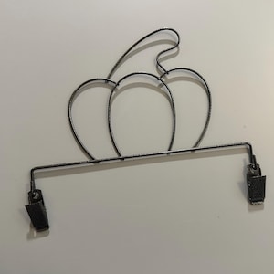 May include: Black metal pumpkin-shaped towel rack with two clips.