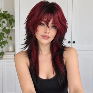 May include: A layered wig featuring a dark black base with vibrant deep red highlights throughout. The hair is styled with a shaggy cut, curtain bangs, and face-framing layers that reach past the shoulders, creating a textured and voluminous appearance.