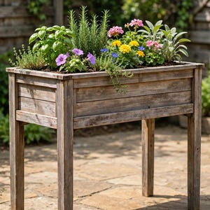 Könnte beinhalten: Ein rechteckiges, erhöhtes Pflanzgefäß aus Holz auf vier Beinen, gefüllt mit einer Vielzahl grüner Kräuter und bunter Blumen, darunter violette, gelbe und rosa Blüten. Das Pflanzgefäß besteht aus verwitterten, braunen horizontalen Holzbrettern.