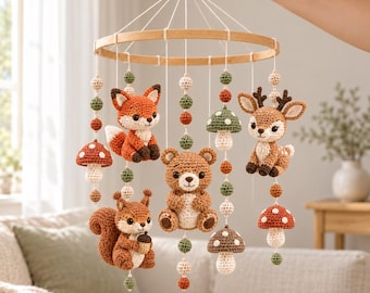 May include: A nursery mobile featuring crocheted woodland animals and mushrooms suspended from a circular wooden frame. The figures include a fox, a bear, a squirrel, and a deer, interspersed with small crocheted spheres in green, orange, and cream.