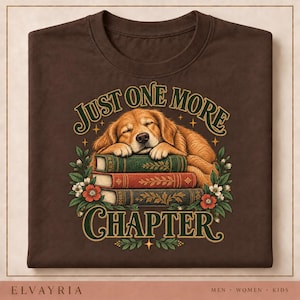 May include: A dark brown t-shirt featuring a graphic of a golden-colored dog sleeping on a stack of three books. The text "JUST ONE MORE CHAPTER" is printed in green and gold. The design includes green leaves and red and white flowers.