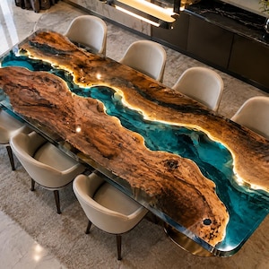 May include: A rectangular dining table featuring two large, natural-edged wood slabs separated by a central, translucent blue resin river inlay. The resin section is illuminated from within by integrated warm LED lighting, surrounded by eight beige chairs.