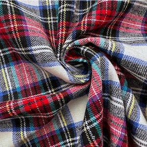 May include: A fabric featuring a multi-colored plaid pattern with intersecting lines in red, white, black, blue, and yellow. The material is gathered in a central swirl, showcasing the repeating tartan design and the texture of the woven textile.
