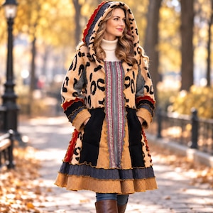 May include: A hooded coat featuring a tan and black leopard print upper section, a central zip with patterned trim, and a multi-layered skirt with black, grey, and mustard yellow knit panels with ruffled edges and long sleeves.