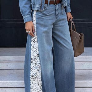 May include: A blue denim jacket and matching wide-leg denim jeans featuring a vertical white lace panel along the outer side of the leg. The outfit includes a white t-shirt, a brown leather belt, and a brown handbag.