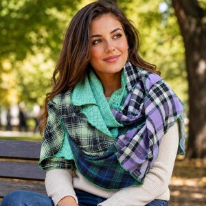 May include: A multi-textured scarf featuring a patchwork design of green, purple, and navy blue plaid fabric panels combined with solid mint green knit sections. The scarf has a layered, asymmetrical construction with visible stitched seams.