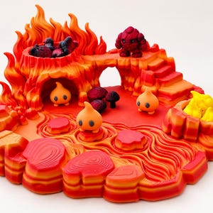 May include: A multi-level volcanic landscape figurine featuring a red and orange lava flow, sculpted rock formations, and three small orange flame-like creatures. A dark red stone figure stands on a bridge above a cave entrance.