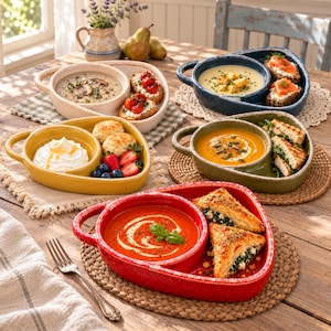 May include: Four ceramic soup and sandwich serving dishes in red, yellow, green, and blue. Each oval-shaped bowl features a divided section for soup and a side compartment for bread, pastries, or fruit, arranged on a wooden table.