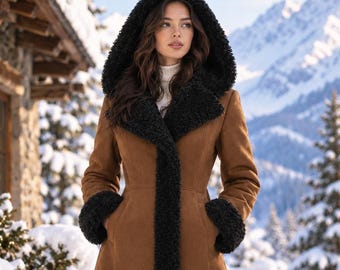 May include: A long, tan coat featuring a black faux-shearling hood, wide lapels, and cuffs. The coat has a structured, fitted bodice that flares into a full-length skirt, with black trim along the front opening and the bottom hemline.