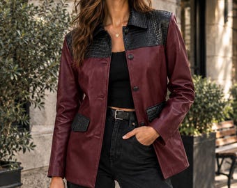 May include: A burgundy jacket featuring a black crocodile-textured collar and pocket flaps, long sleeves, and a front button closure. The jacket is worn over a black top and black jeans, paired with a black handbag and black sunglasses.