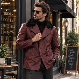 May include: A double-breasted burgundy leather jacket featuring a black faux fur collar, long sleeves, and dark buttons. The jacket is worn over a black turtleneck sweater, paired with dark trousers and black sunglasses.