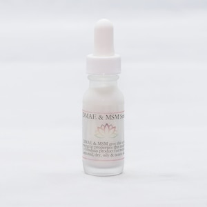 以下が含まれることがあります： 白いドロップ付きの透明なガラス瓶で、ラベルには「DMAE & MSM Serum」と記載されています。ラベルには、ピンクと白の蓮の花と、「DMAE & MSMは、この美容液にエネルギーを与える特性を与え、成熟した、色付きの、乾燥した、油っぽい、そしてにきびのある肌のための素晴らしい製品にします。」というテキストも含まれています。