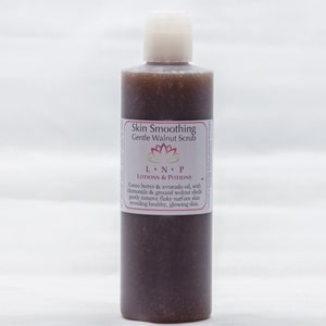 Puede incluir: Una botella de vidrio marrón con una tapa blanca y una etiqueta que dice "Skin Smoothing Gentle Walnut Scrub LON.P LOTIONS & POTIONS Cocoa butter & avocado oil, with chamomile & ground walnut shells gently remove flaky surface skin revealing healthy, glowing skin."