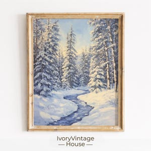 Könnte beinhalten: Ein gerahmtes Ölgemälde, das eine Winterlandschaft mit schneebedeckten immergrünen Bäumen entlang eines gewundenen blauen Bachs zeigt. Die Szene zeichnet sich durch weiches Licht aus, das durch den Wald fällt, mit weißen Schneebänken und einem hellblauen Himmel.