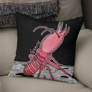 Op de afbeelding: Een zwart kussen met een roze en witte illustratie van een termiet. De tekst "Termite" staat in wit op het kussen.