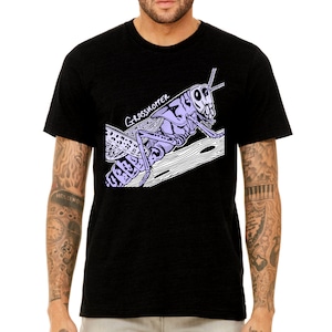 May include: Black t-shirt featuring a purple and white illustration of a grasshopper on a branch. The text "Grasshopper" is written in white above the grasshopper.