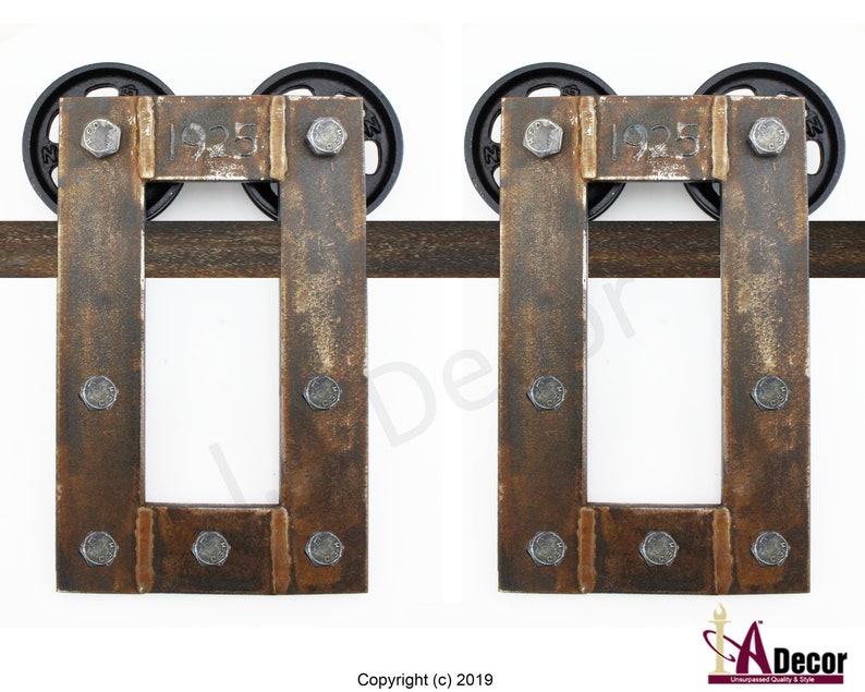 May include: Two rectangular metal barn door hangers featuring a weathered brown finish and exposed silver bolts. Each hanger is stamped with the year 1925 and includes two black circular wheels positioned on a horizontal metal track rail.