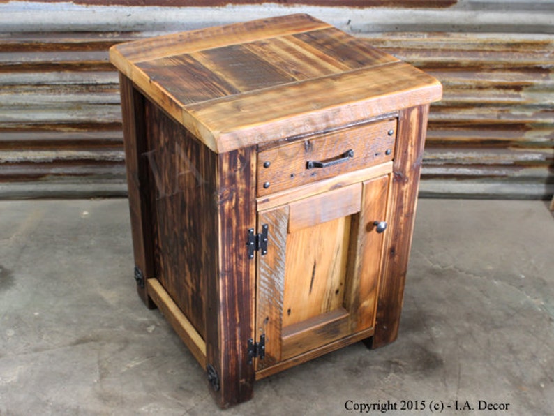 May include: A rustic wooden nightstand with a single drawer and a cabinet door. The nightstand is made of reclaimed wood and has a dark brown finish. It features black metal hardware and a distressed look.