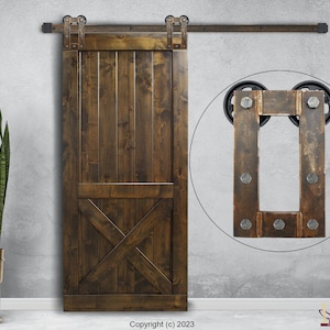 May include: A dark brown wooden sliding barn door featuring vertical planks and a lower X-brace design. The door is mounted on a black metal track system with exposed rollers. A circular inset shows a close-up of the metal hardware with bolts.