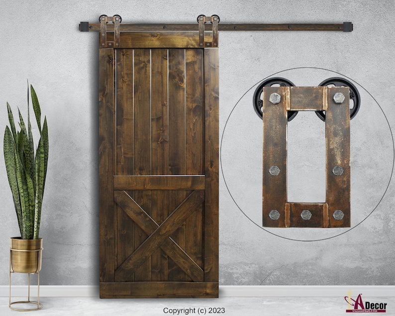 May include: A dark brown wooden sliding barn door featuring vertical planks and a lower X-brace design. The door is mounted on a black metal track system with exposed rollers. A circular inset shows a close-up of the metal hardware with bolts.