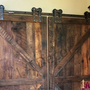 May include: A pair of double sliding barn doors crafted from dark brown reclaimed wood, featuring a diagonal cross-brace design and mounted on a black metal track system with exposed industrial-style rollers and hardware.
