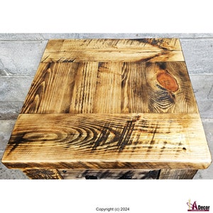 May include: Rustic wooden table top with a distressed finish. The wood has a natural brown color with dark brown knots and grain patterns. The table top is made of several planks of wood that are joined together.