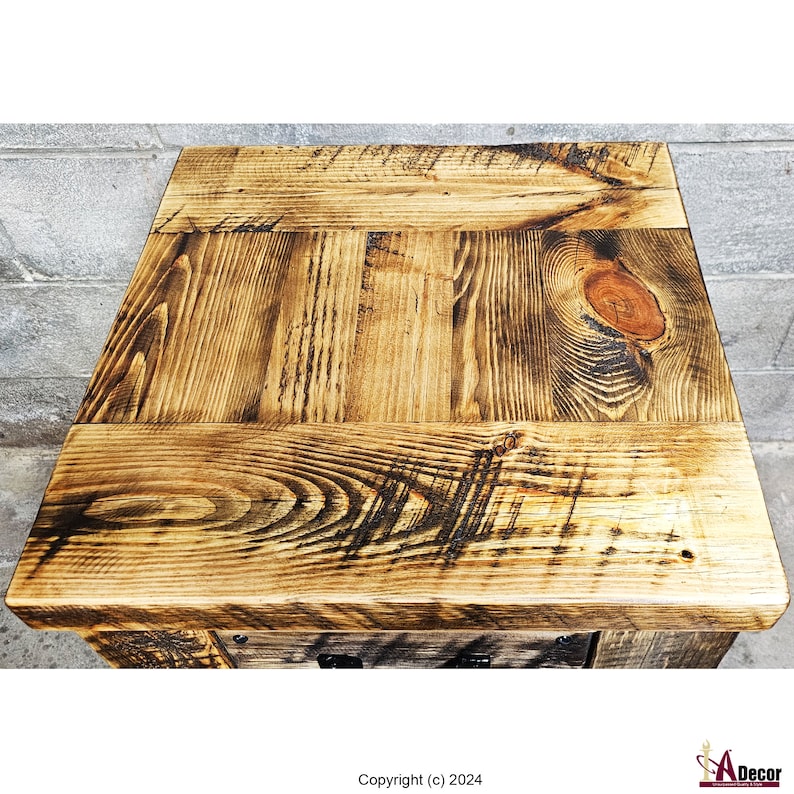 May include: Rustic wooden table top with a distressed finish. The wood has a natural brown color with dark brown knots and grain patterns. The table top is made of several planks of wood that are joined together.