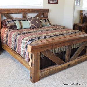 May include: A handcrafted wooden bed frame with a distinctive headboard design. The bed is constructed from reclaimed wood and includes a matching bedside table. The bedding features a patterned comforter with bear motifs and decorative cushions.