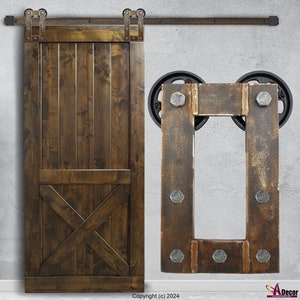 May include: A dark brown wooden sliding barn door with vertical planks and a lower X-brace design, featuring a black metal top rail and rollers. Beside it is a rectangular metal mounting plate with six visible bolts and two black wheels.