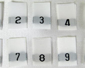 May include: Ten white fabric tags with black numbers 1 through 10 printed on them. The tags are arranged in two rows of five.