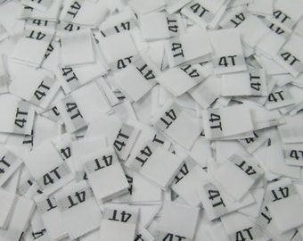 May include: A pile of white fabric tags with the number "4T" printed on them.