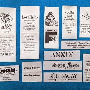 May include: A collection of white fabric clothing labels with black text and graphics. The labels include brand names, care instructions, size information, and fabric content. Some of the labels feature a rose, a turtle, a teapot, and a stylized illustration of a person.