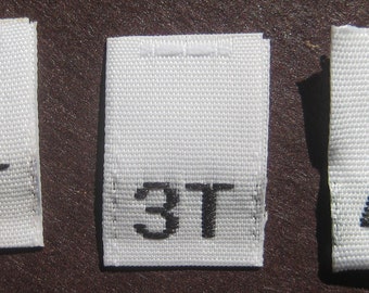 May include: Three white fabric tags with black text. The tags are labeled "2T", "3T", and "4T".