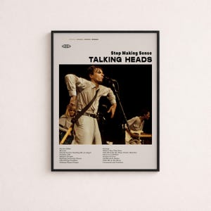 May include: A framed poster featuring a black and white concert photograph of the band Talking Heads performing Stop Making Sense. The text includes the band name, album title, and a tracklist. The design uses a cream background with black text.