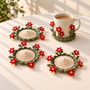 May include: Three round crochet coasters and one matching crochet mug cozy, each featuring a cream-colored center, a scalloped sage green border, and small red flowers with yellow centers attached around the outer edges.