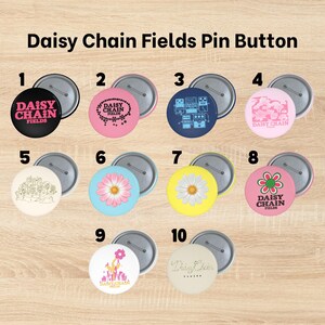 May include: Ten circular pin buttons labelled Daisy Chain Fields, featuring various designs including text, floral patterns, and guitar pedal illustrations in colours like black, pink, blue, yellow, and white, each with a metal pin back.