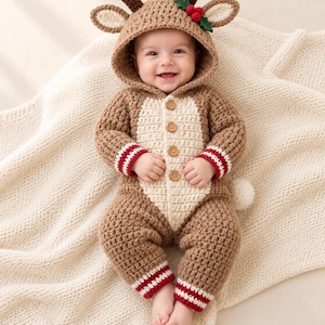 Op de afbeelding: Een gehaakte onesie met capuchon in bruin en crème, voorzien van rendiergeweien, oren en een hulstbes-accent op de capuchon. Het kledingstuk heeft een crèmekleurig voorpand, vier houten knopen en rood-wit gestreepte boorden aan de mouwen.